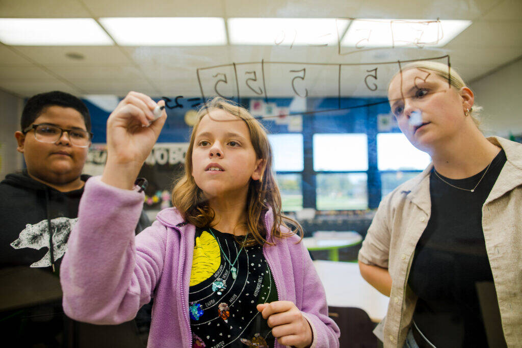 A group of girls writing on a glass board.